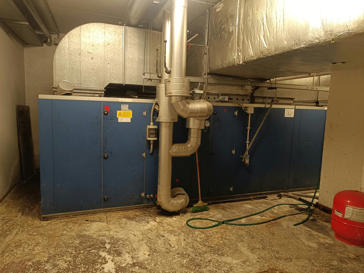 Impianto frigorifero industriale con unità blu e piping in sala tecnica
